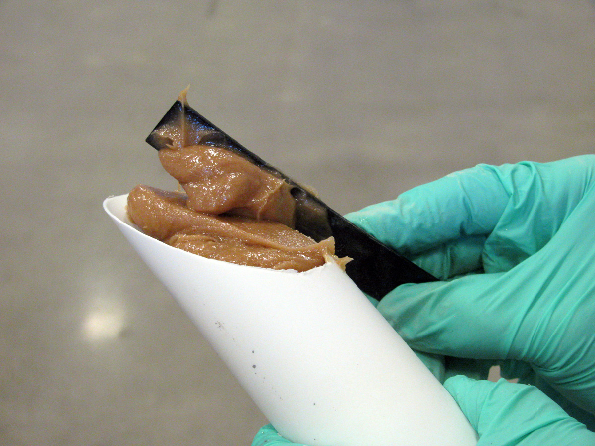Thickened epoxy being loaded into an applicator tube on a workbench