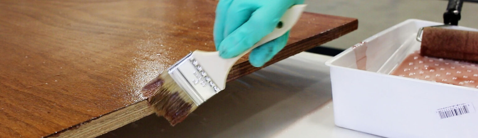 A coating being brushed along a timber surface previously sealed with epoxy.