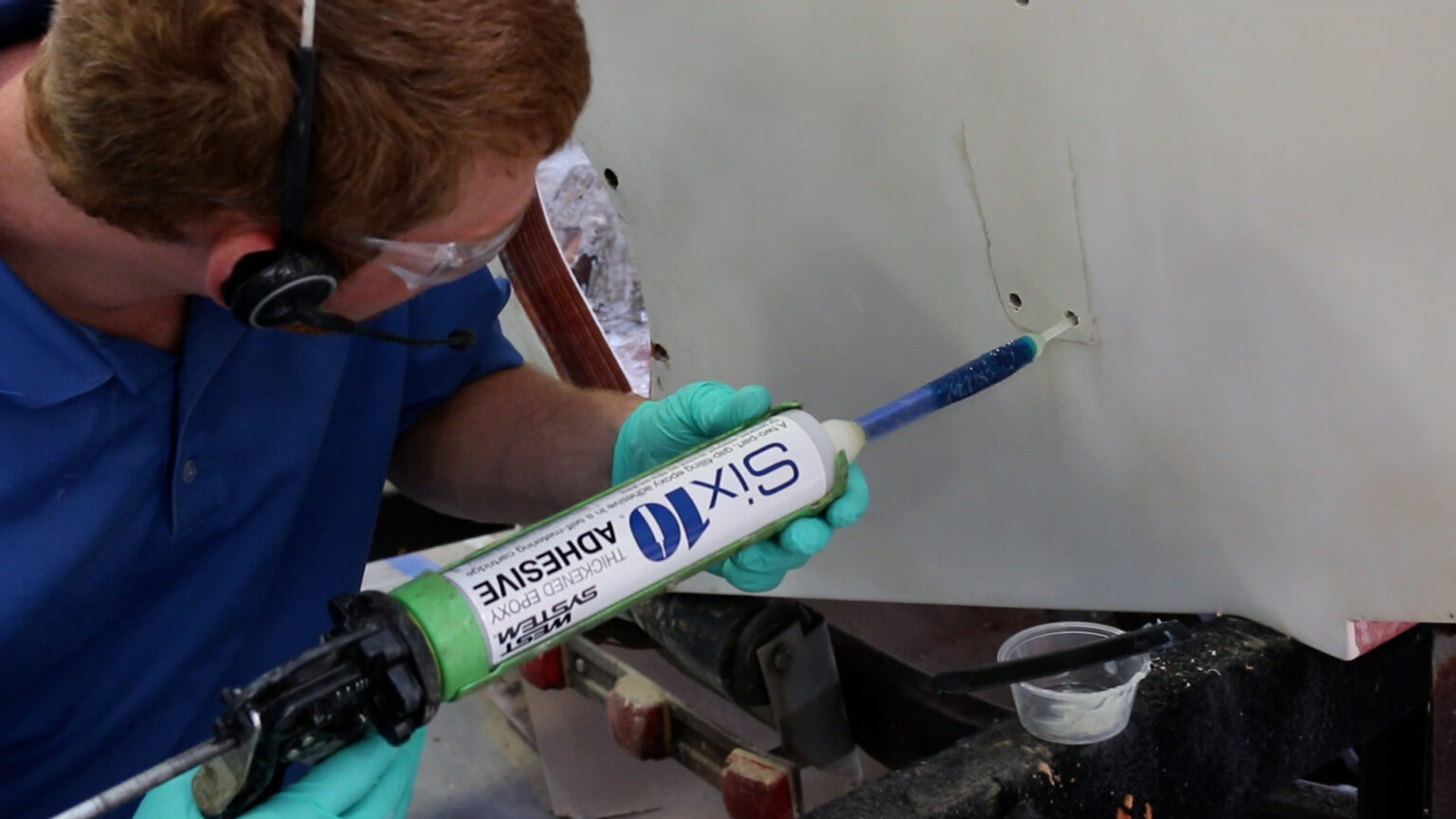 Applying thickened epoxy adhesive to the base of a fitting before installing it.